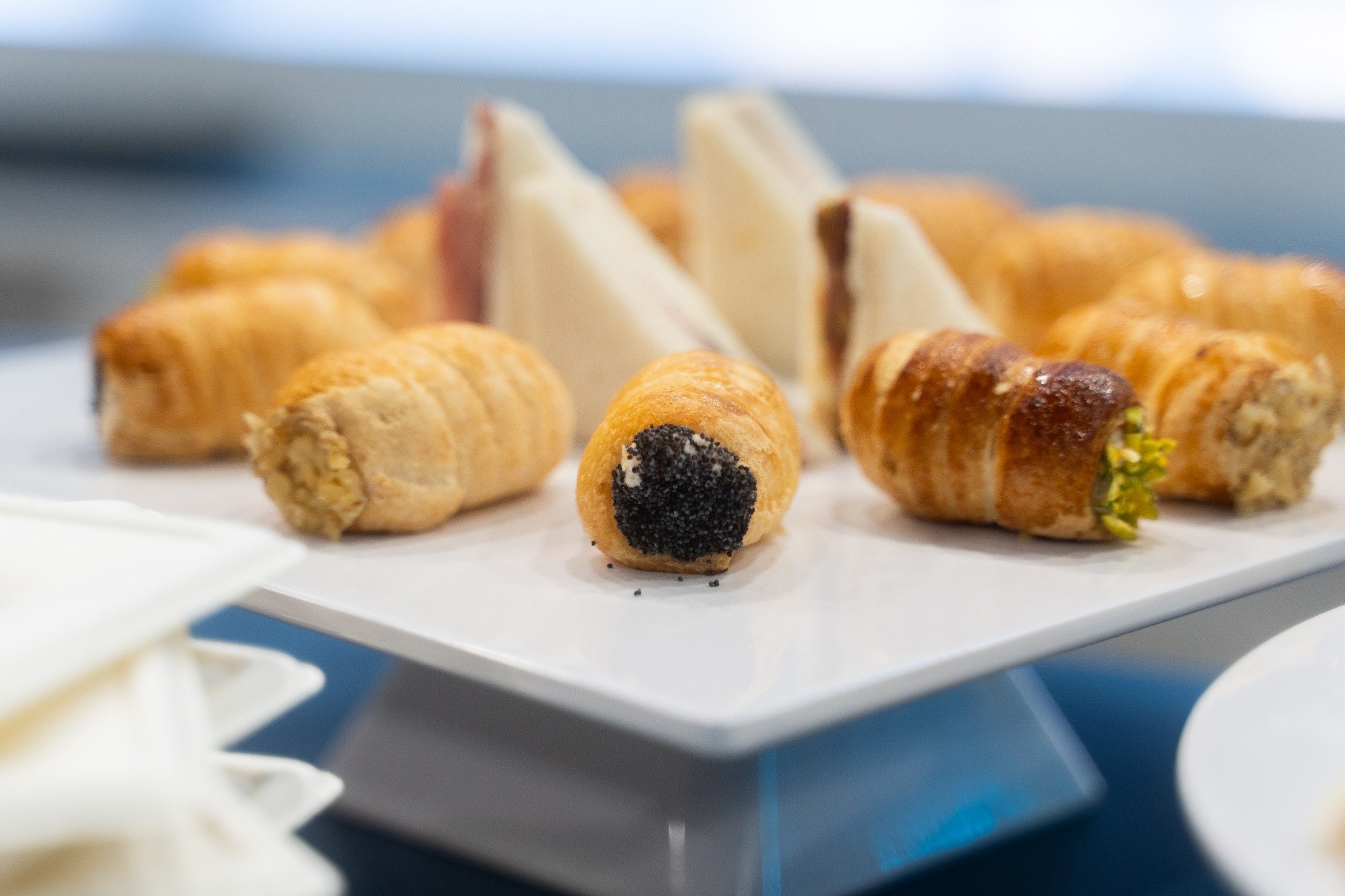 Finger food salati, cannoncini farciti e tramezzini su alzata bianca per catering fieristico