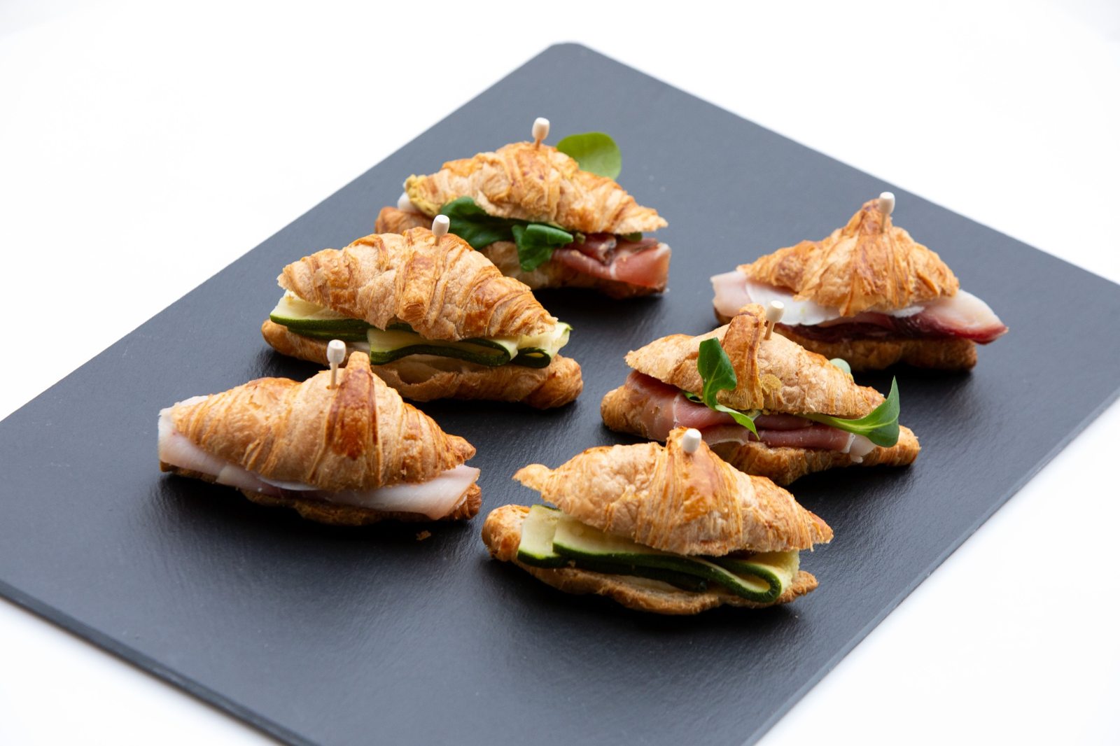 Mini croissant salati farciti presentati su vassoio in ardesia per catering fieristico