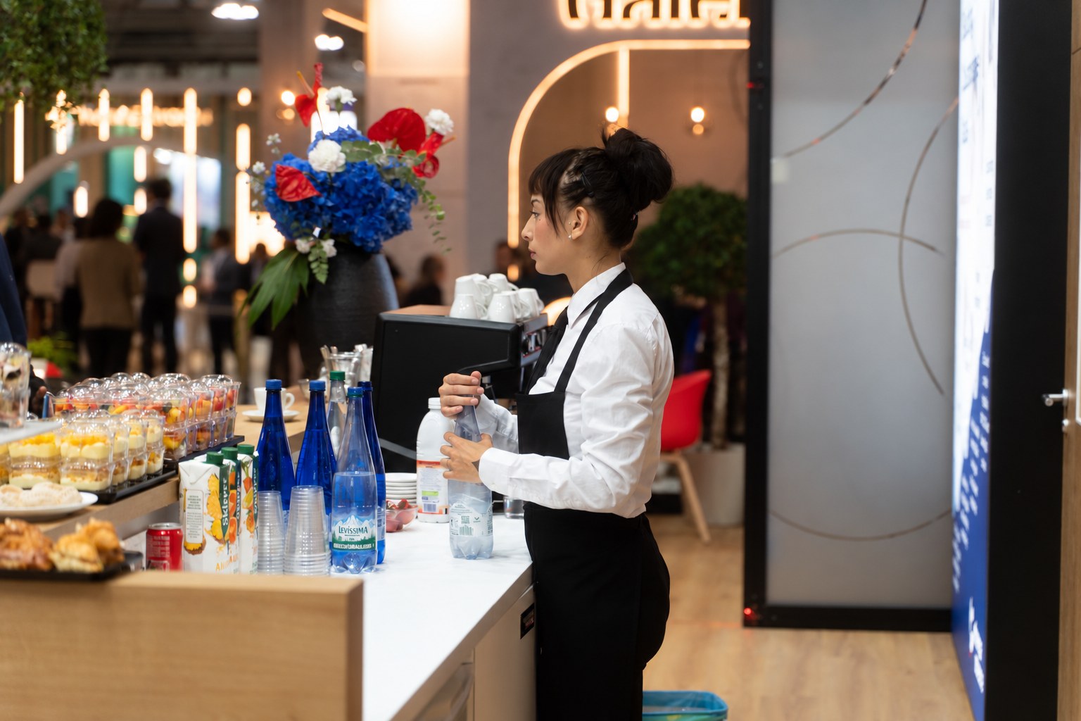 Addetta al servizio bar durante un evento fieristico a Milano con banco catering e bevande